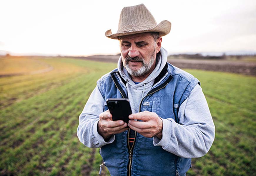 Worker on his smartphone out in the field at work