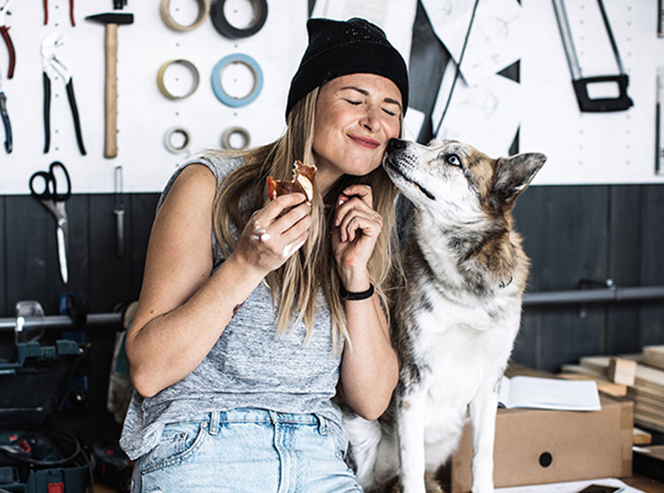 Young female business owner enjoys a snack with her dog nearby