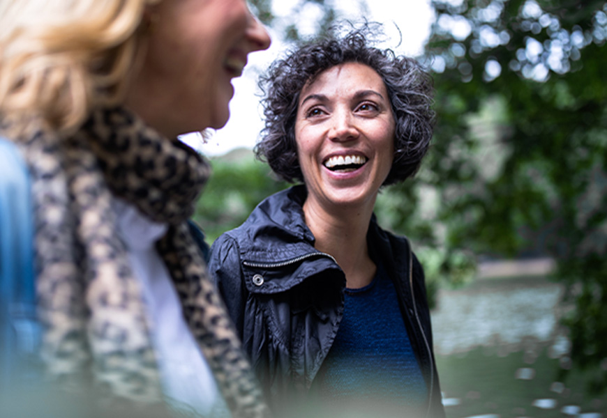 Older woman smiling with her friend while walking outdoors